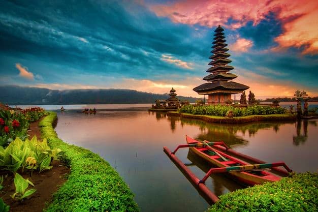 Bali Honeymoon Dreams Balinese temple reflected in calm water at sunset with traditional red boats and lush green vegetation along the shore